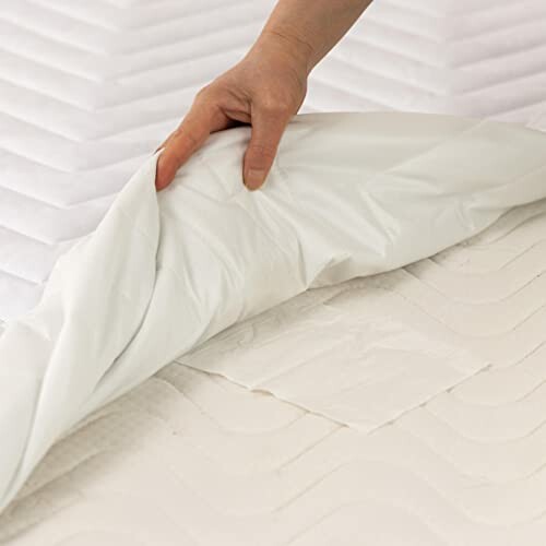 Hand adjusting a white mattress cover